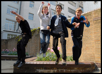 4 teenagers jumping off a small wall