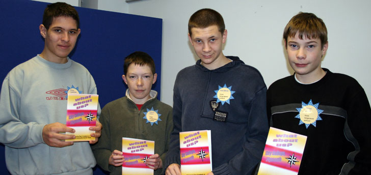 4 teenage boys each holding a 'What about us?' booklet.