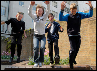 4 teenagers jumping off a low wall