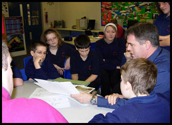 Teacher and pupils sat round a table discussing documents