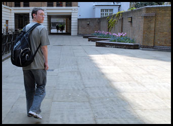 Teenager walking towards a building with a rucksack on his back