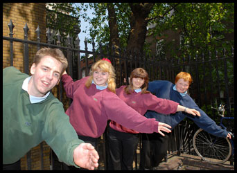 4 teenagers holding onto a street railing.