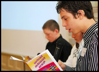 Teenage boy reading from a booklet and speaking into a microphone