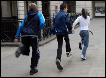 3 teenagers running along a paved area