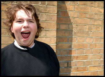 Teenager stood against a brick wall shouting